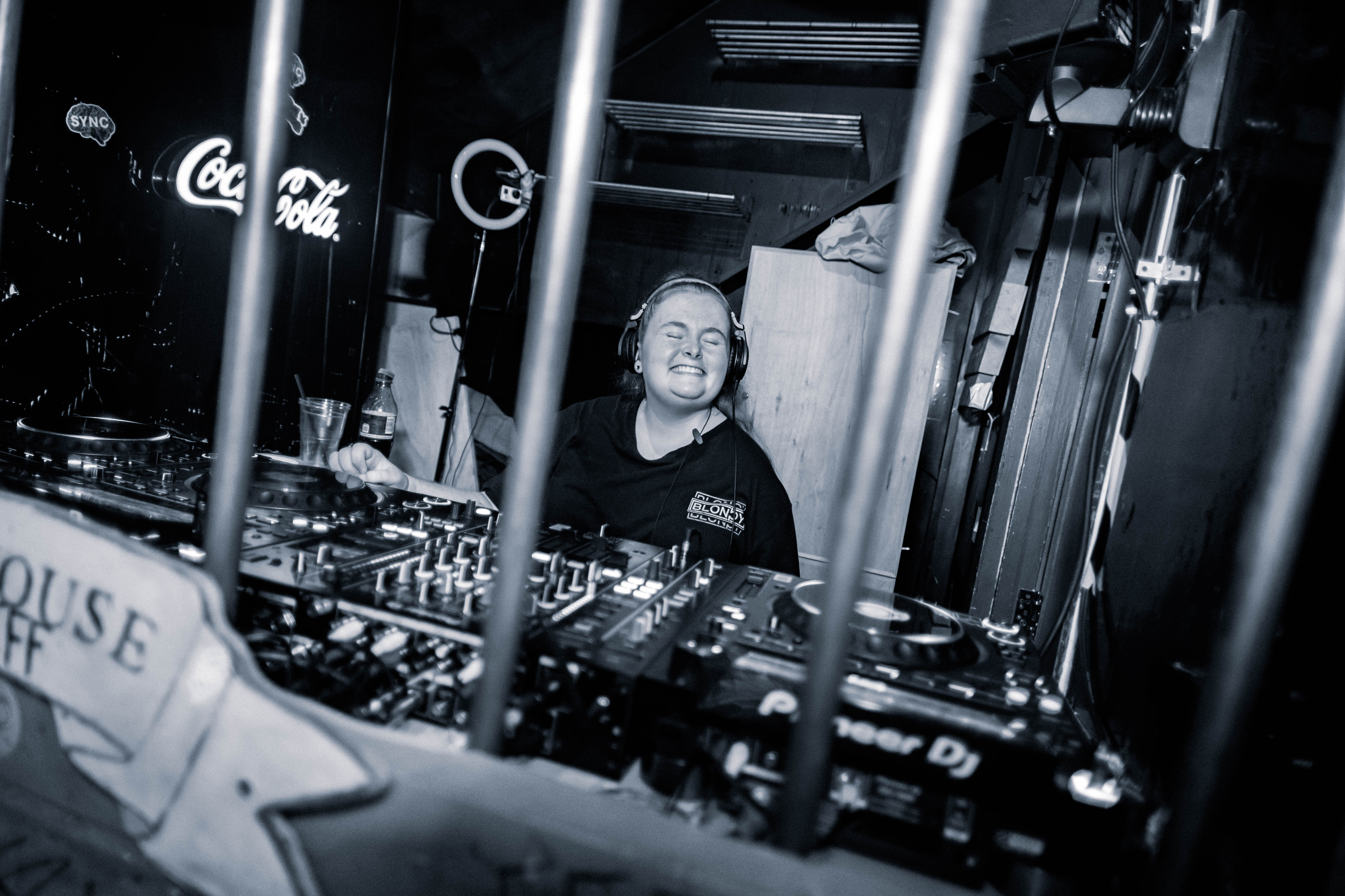 Blondy in the DJ booth smiling at the camera