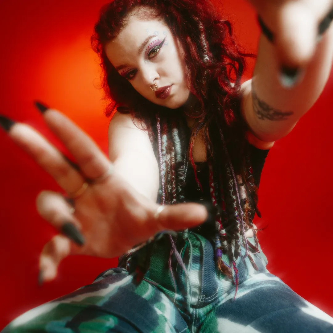  Rhi’N’B on a red background looking at the camera 