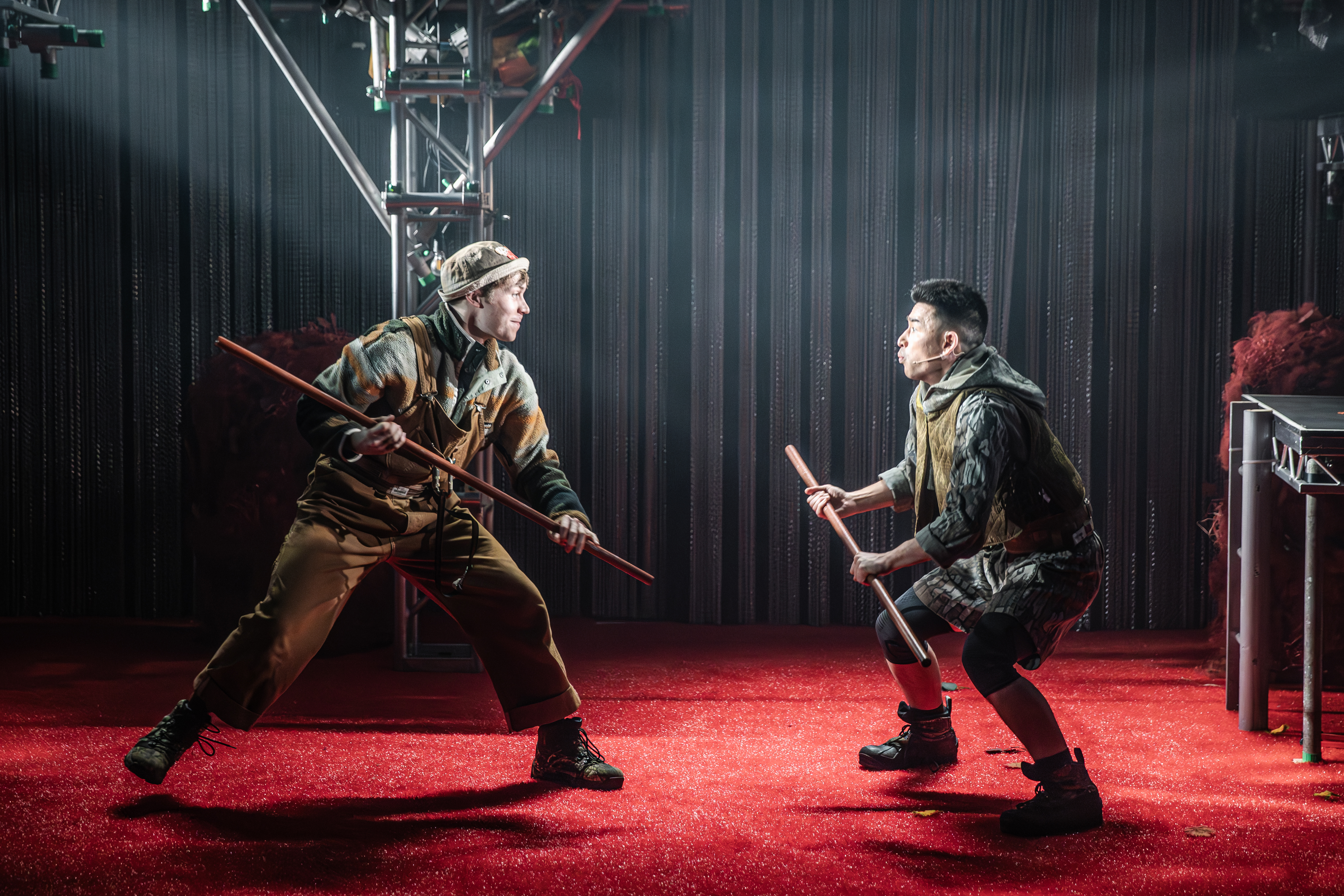 Tom performing on stage in costume facing off with another actor