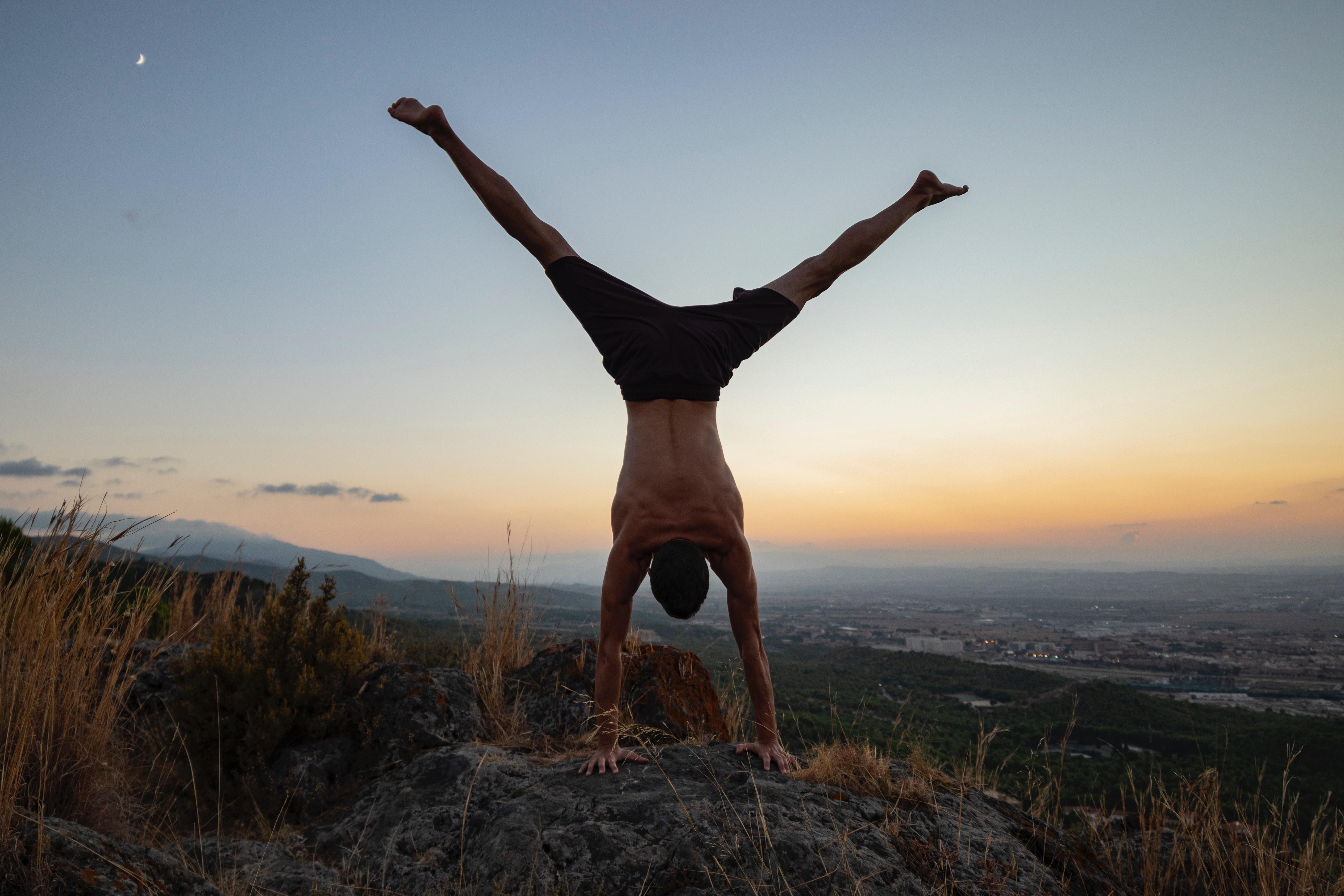 man doing a handstand at sunset