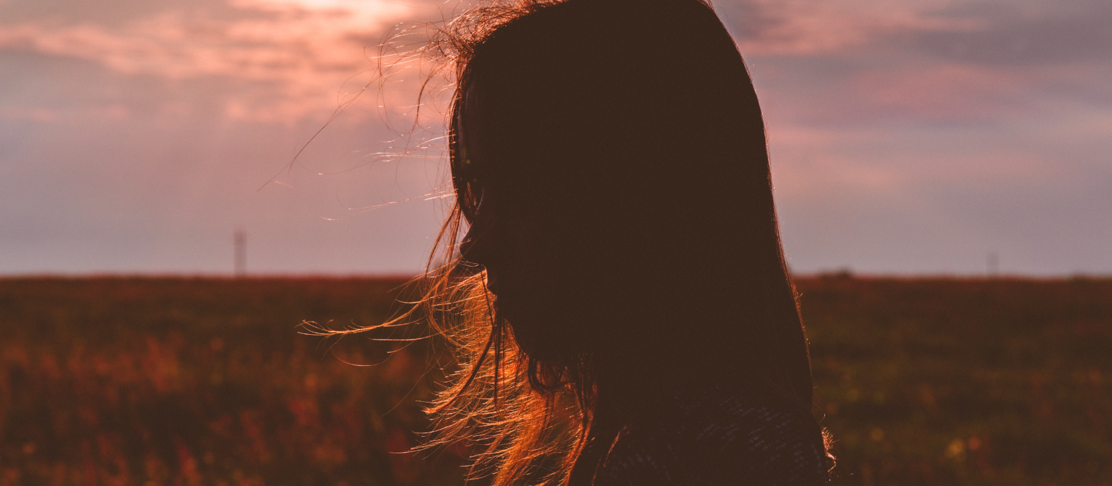 silhouette of a young woman's face against a sunset backdrop