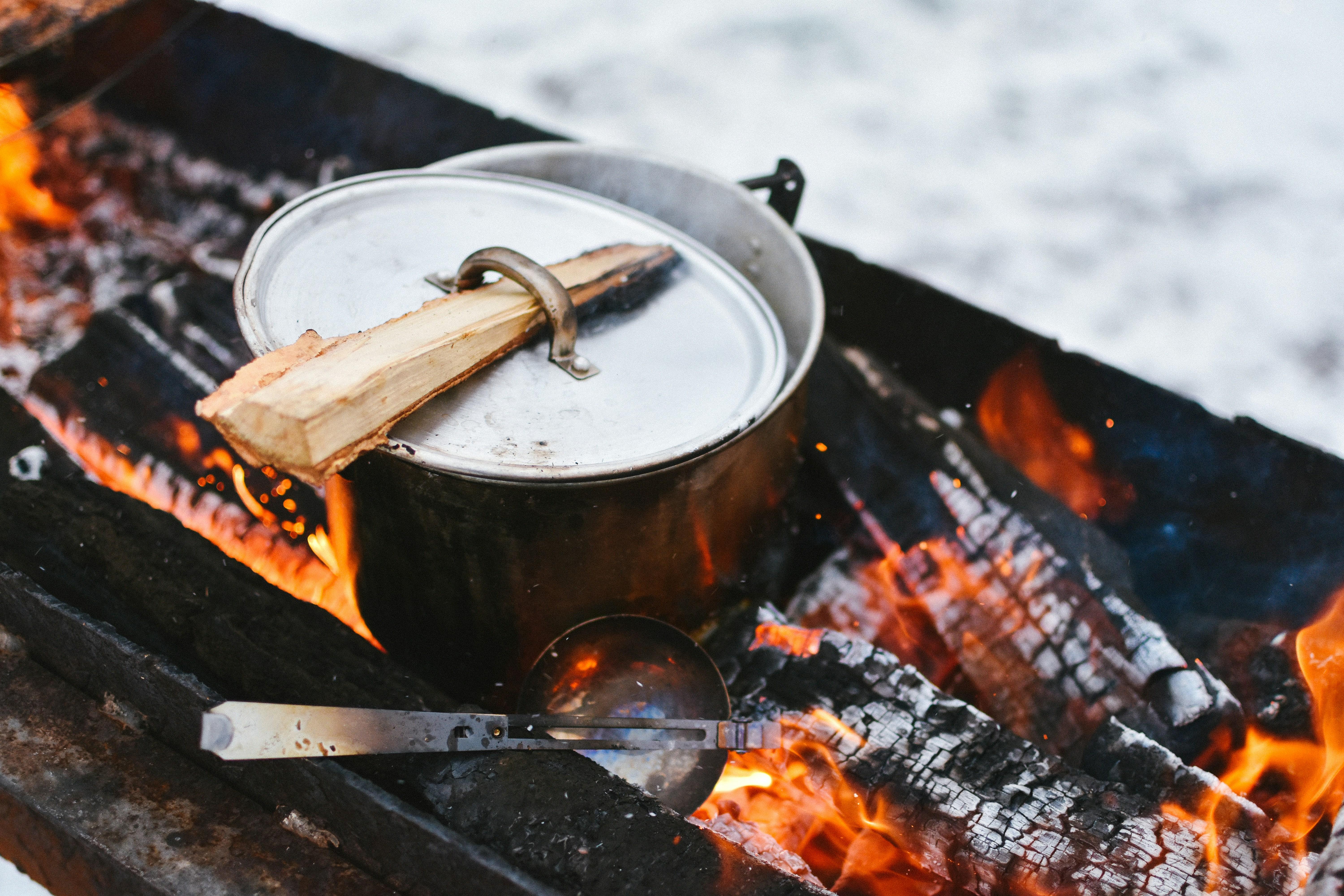 a pot with a lid sitting over a campfire