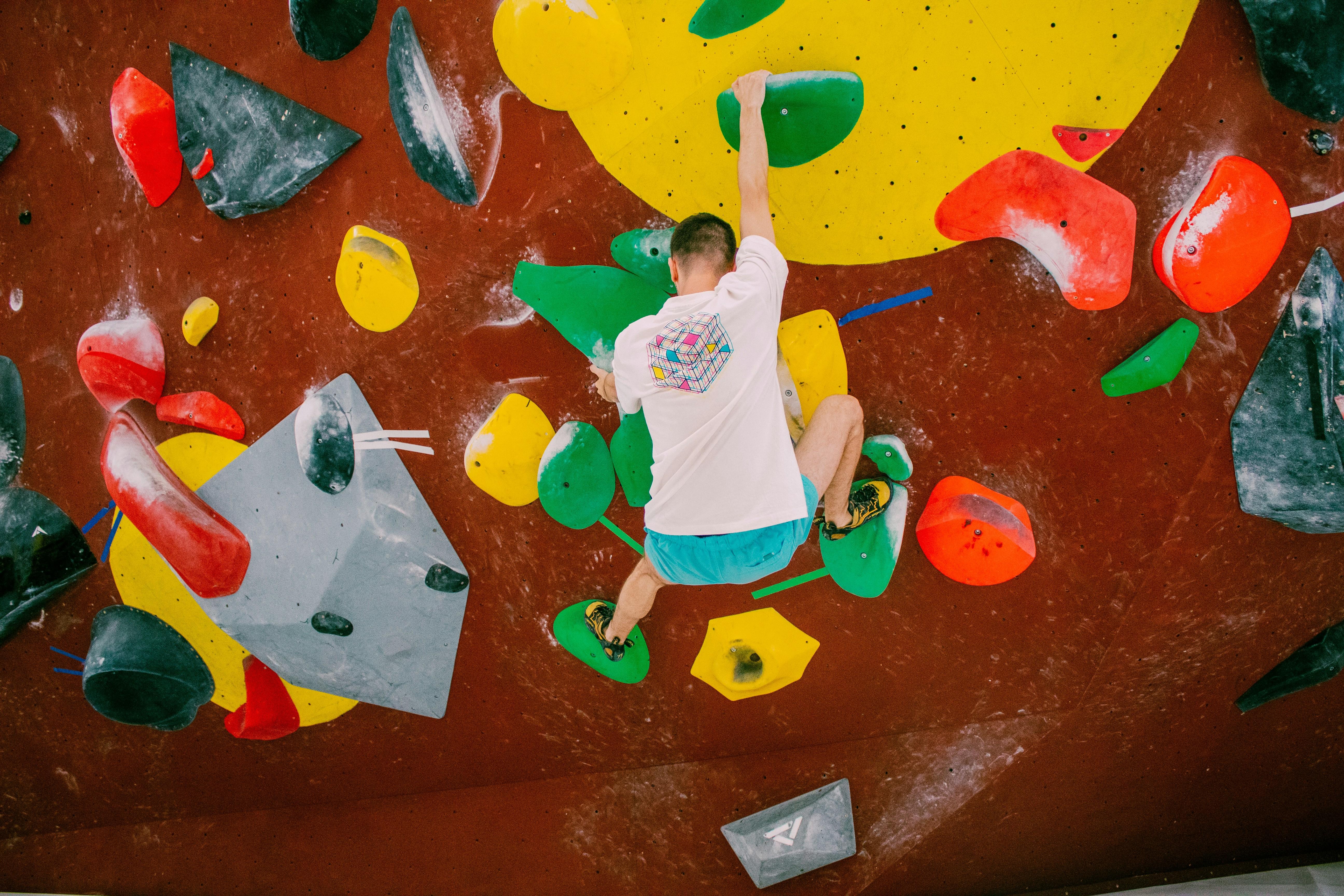 young man climbing on a colorful indoor bouldering wall