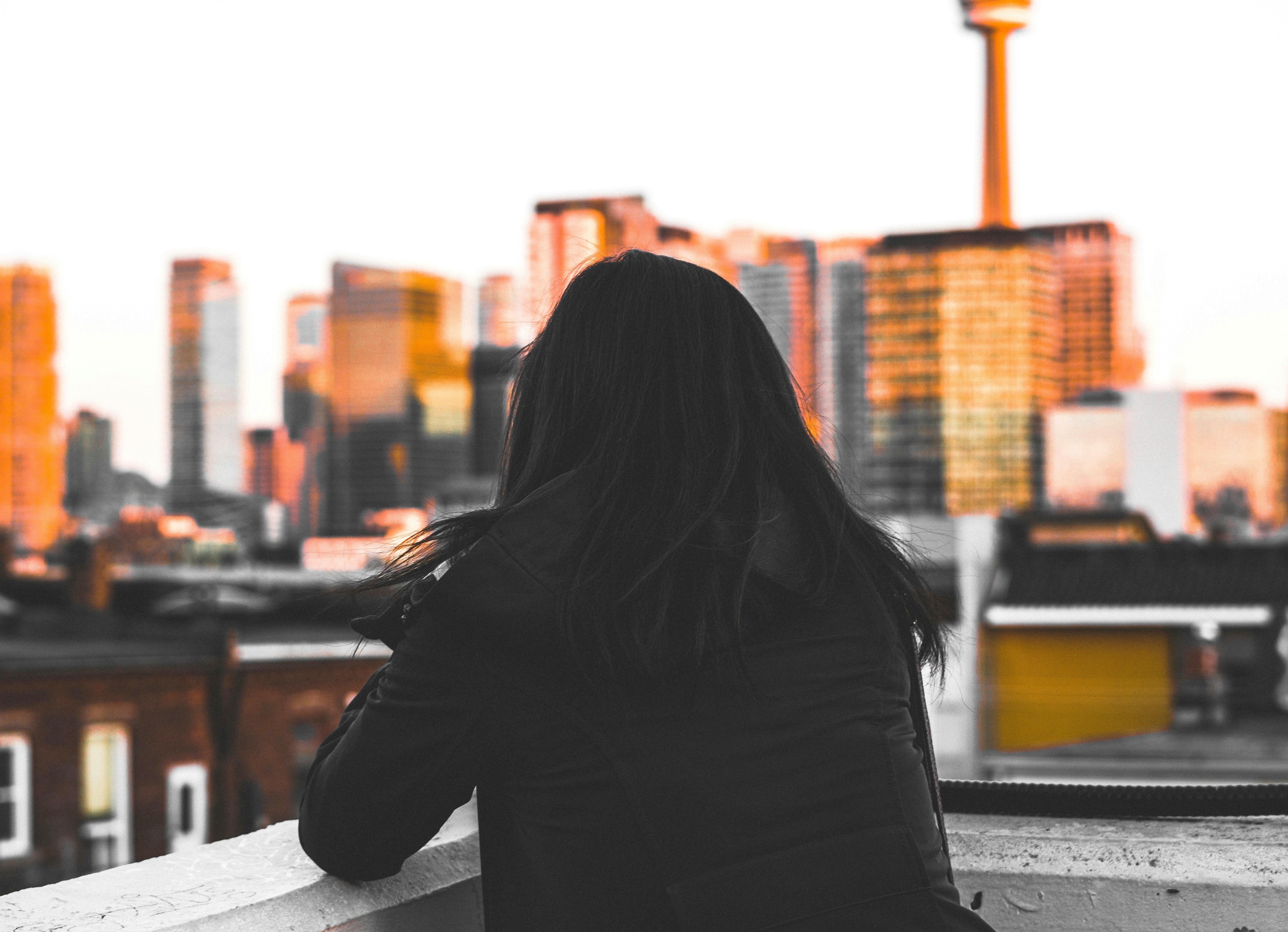 woman standing on a rooftop looking out on a city