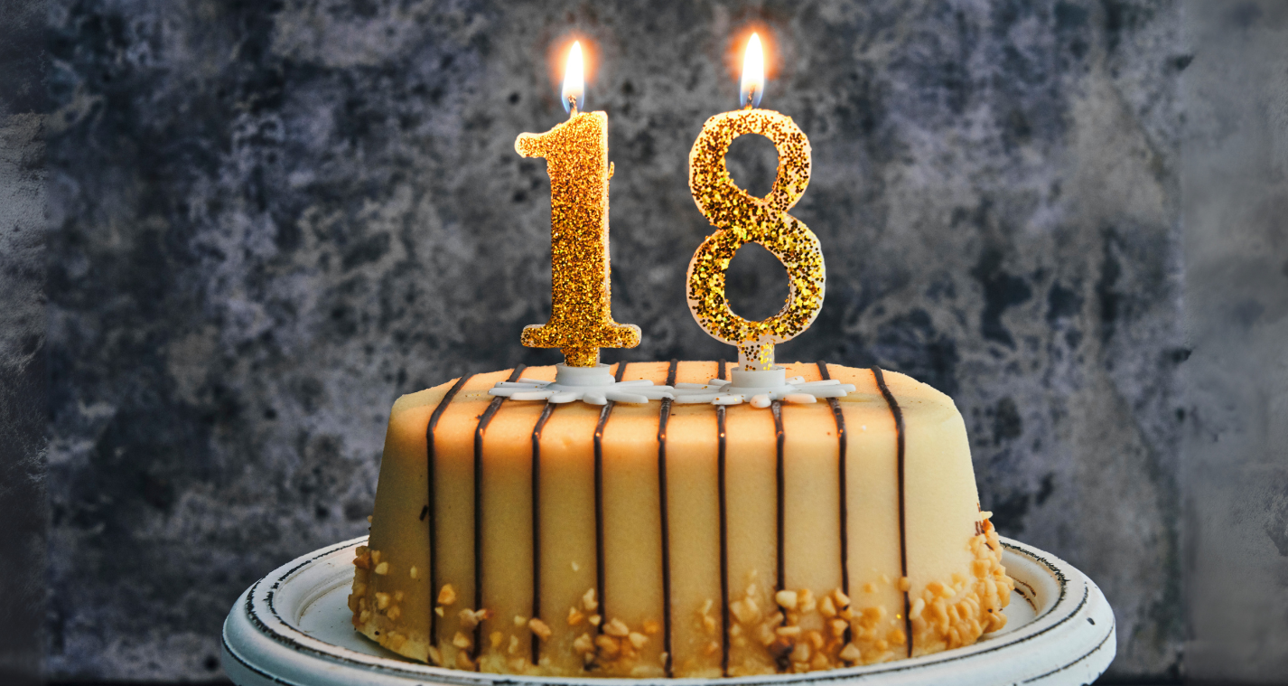 gold birthday cake with 1 and 8 number candles on top, lit