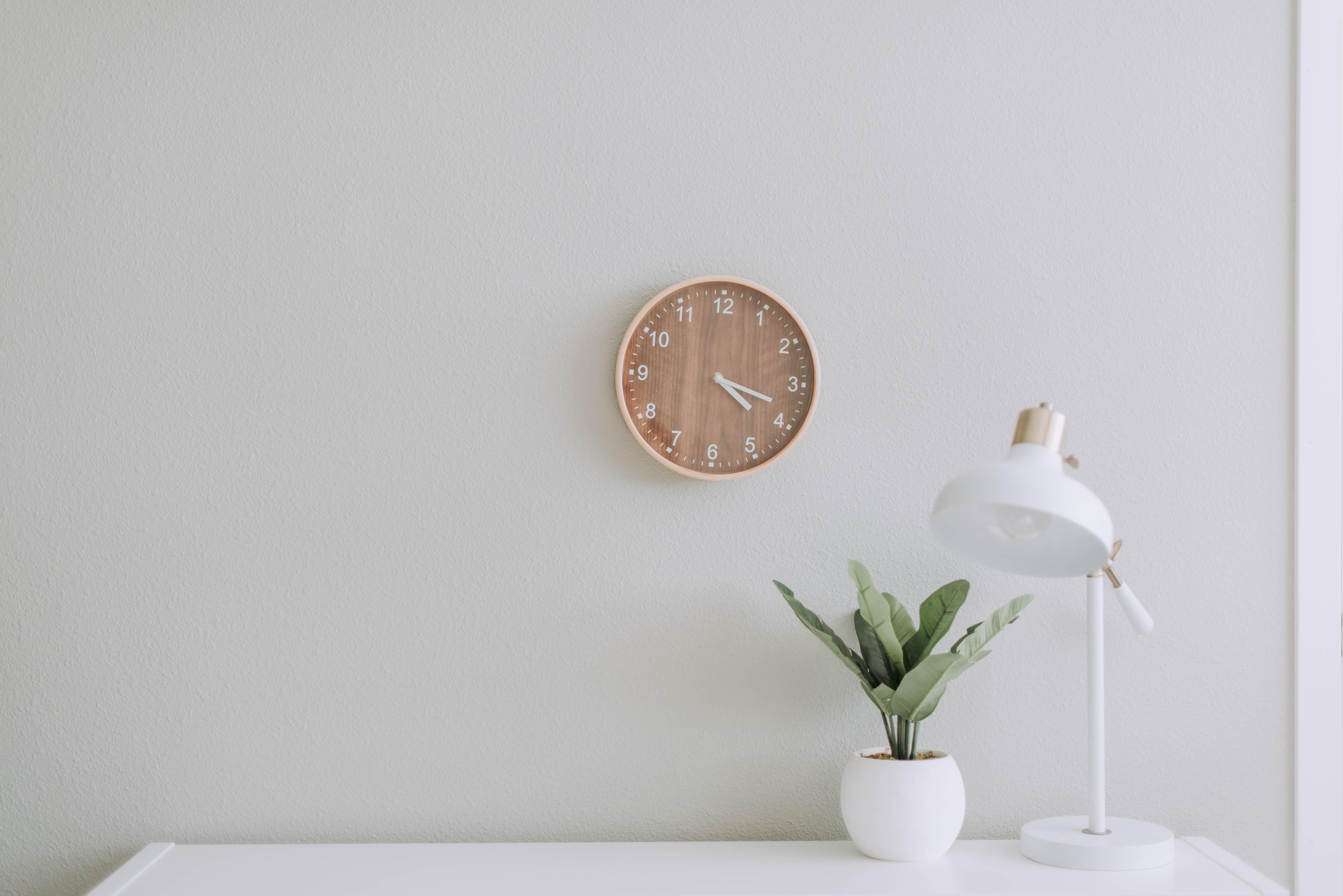 White desk with a white light, plant and clock