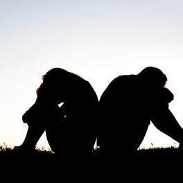 the silhouette of a couple sitting with their backs to each other