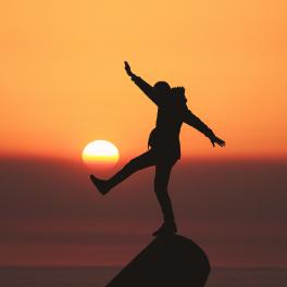 silhouette of a man standing on a cliff against the sunset