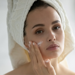 woman looking in the mirror putting on skin cream