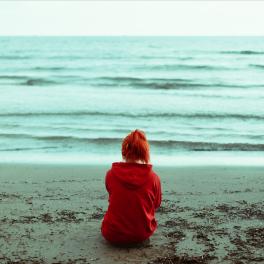 young  person sitting on the beach