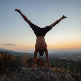 man doing a handstand at sunset