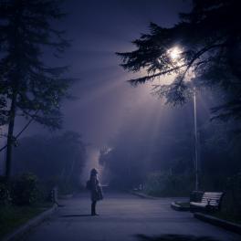 young woman standing under a light post at night