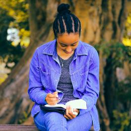 woman sitting on a bench writing 
