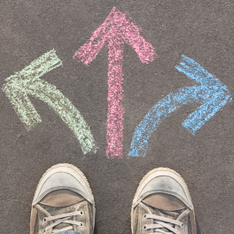 person wearing converse shoes standing in front of 3 chalk arrows point different directions