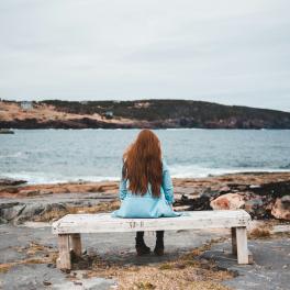 woman sitting on a bench facing the water