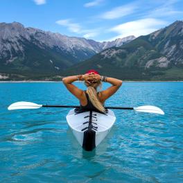 woman kayaking in front of mountains