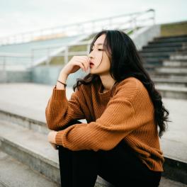 young woman sitting on some bleachers looking out 