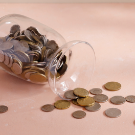 a jar of coins being spilled out on a pink surface