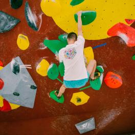 young man climbing on a colorful indoor bouldering wall