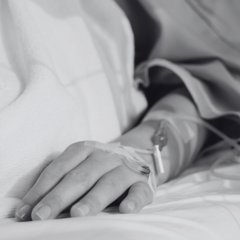 a black and white image of a persons arm hooked up to IVs who is lying in a hospital bed