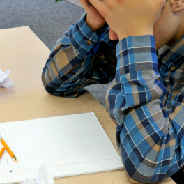 frustrated young man with his head in his hands sitting at a desk