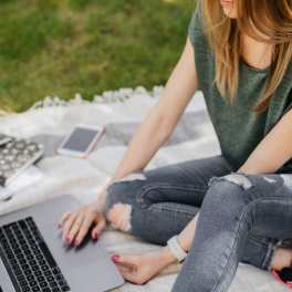 a student sitting on a blanket on the grass studying