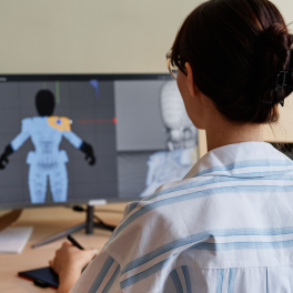woman sitting in front of a computer working on an animated human figure 