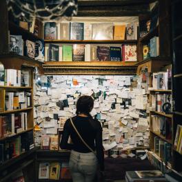 woman standing in a library looking at a board full of pieces of paper