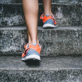 person wearing orange and gray sneakers walking up gray steps