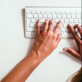 Image of desk and someone typing on a keyboard