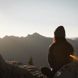 person sitting on a mountain meditating