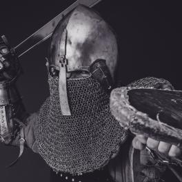 Black and white image of a knight in armor raising his sword