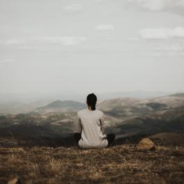 Woman sitting on a cliff looking out onto the view