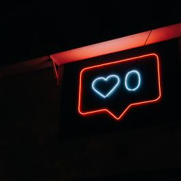 A neon "like" sign on a black background