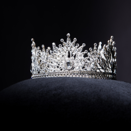 a white crown sitting on a pillow on a black background
