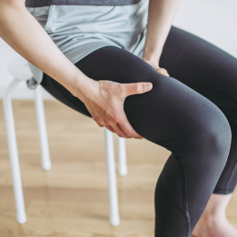 woman sitting on a stool holding her leg