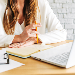 A woman sitting in front of a laptop with a notebook in front of her