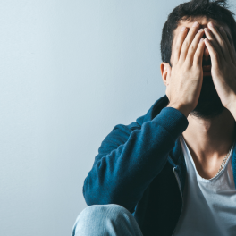 a man sitting on the floor covering his face