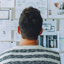 a person sitting facing away from the camera looking at a vision board