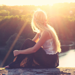 woman sitting on a cliff looking over the water