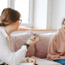 A therapist and a teenage girl sitting on a couch having a conversation