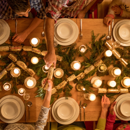 family sitting around a christmas dinner table opening christmas crackers