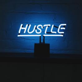 neon light that says "hustle"