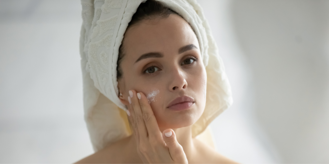 woman looking in the mirror putting on skin cream