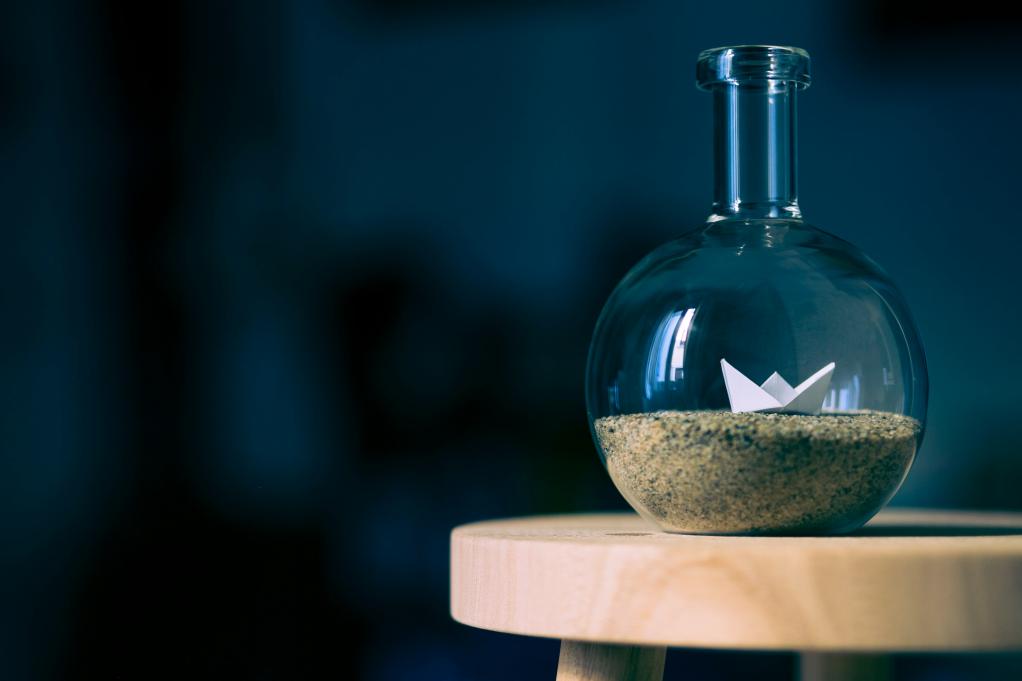 a little paper boat in a glass container 