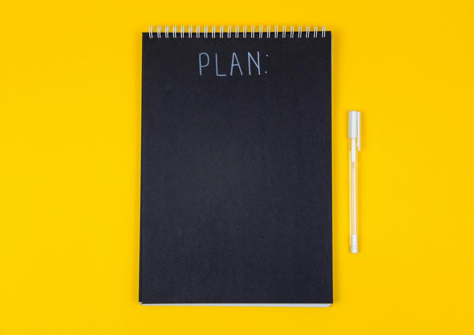 a black notebook that says "Plan" on a yellow background