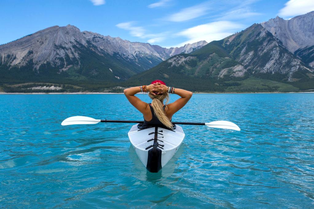 woman kayaking in front of mountains