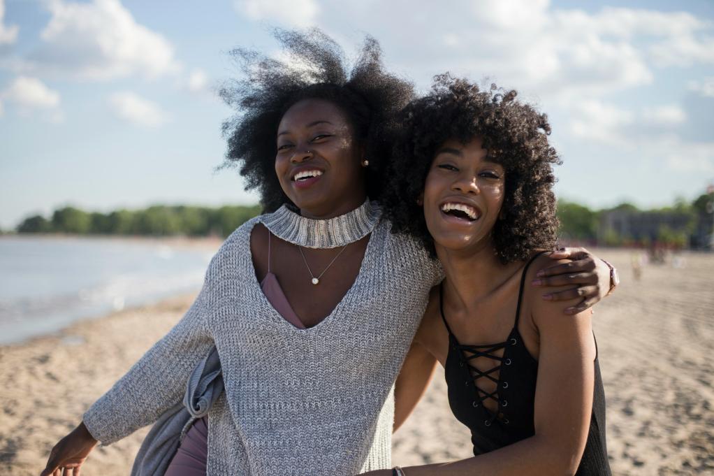 two young women on a beach smiling