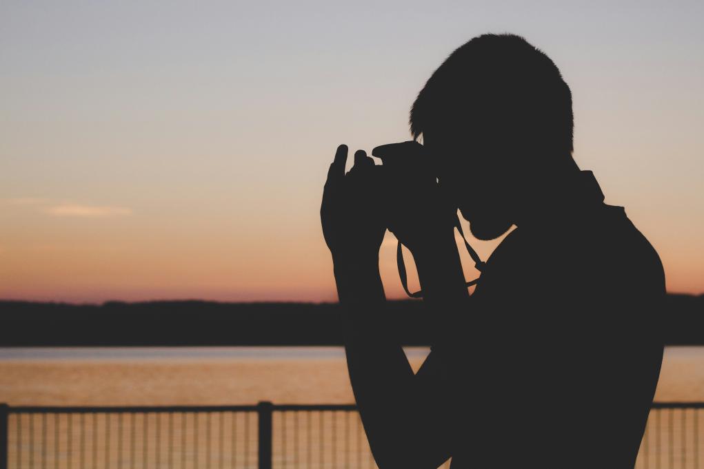 silhouette of a person holding a camera to their face
