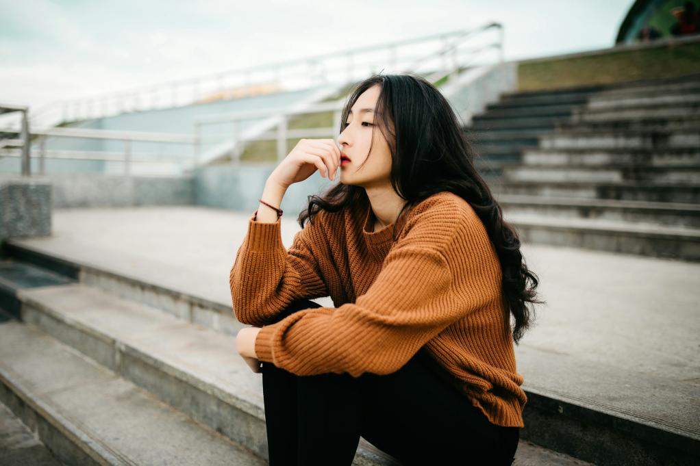 young woman sitting on some bleachers looking out 